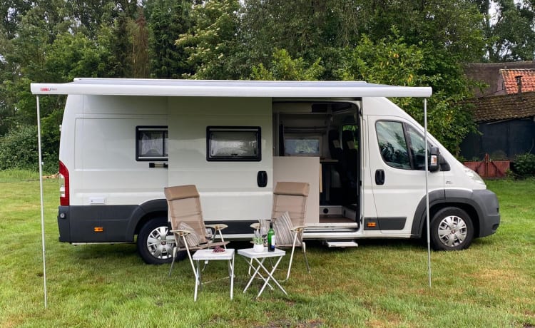 Autobus camper Fiat Ducato con sedili di lusso e un grande letto matrimoniale.