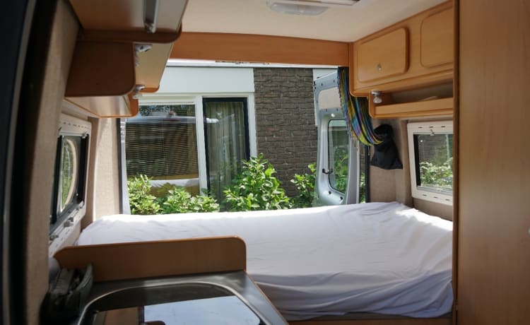 Compact bus camper with large fixed bed