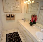Master bath with two sinks and shower over tub and matching art