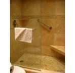 walk-in frameless shower tiled in travetine and beach pebble accents