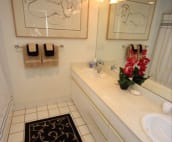 Master bath with two sinks and shower over tub and matching art