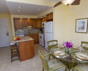 Showing the kitchen, island, and dining table, along with dining area and fan