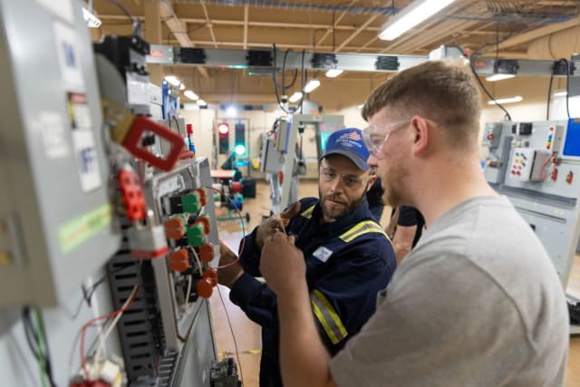 A student and an instructor look at an electrical panel.