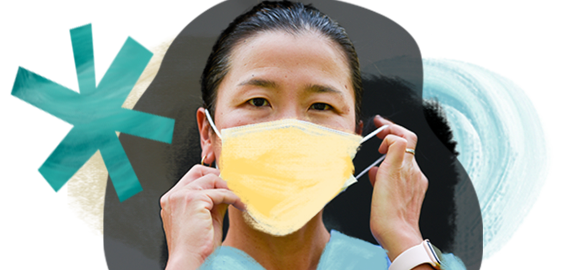 A woman wears medical scrubs and put on a yellow medical mask.