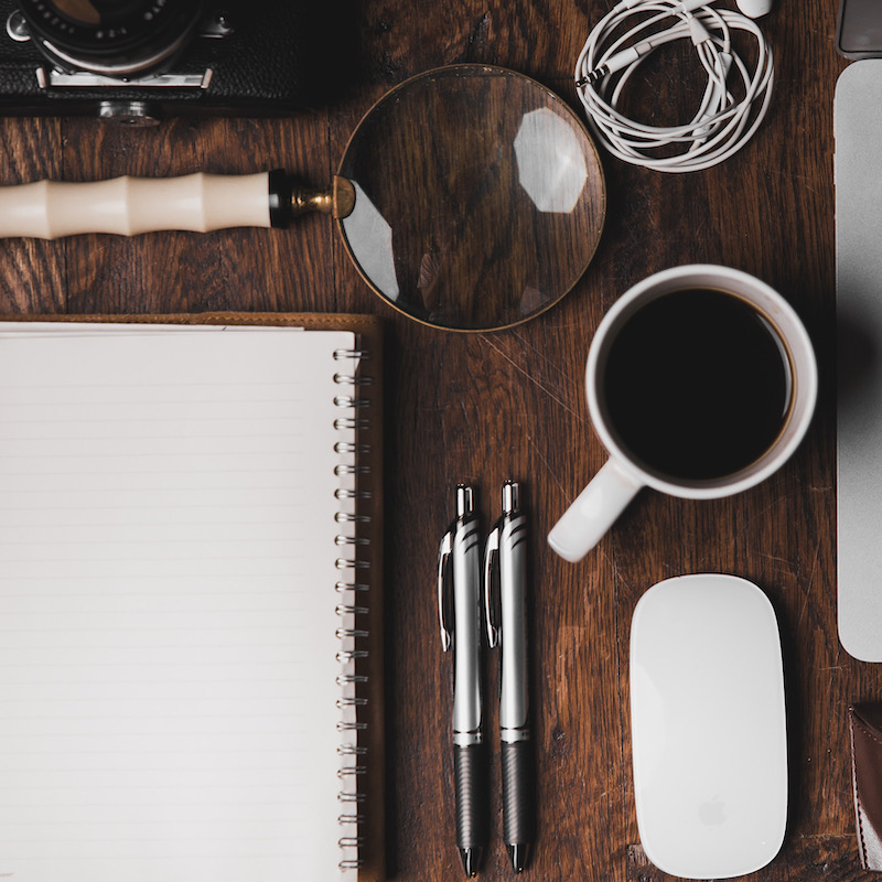 Image of a desk with a laptop. paers and a coffee mug on it. 