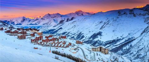 Sunset view of snow-covered chalets and buildings in Les Menuires