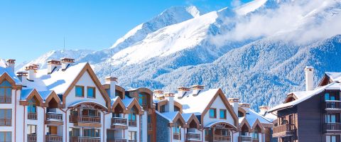  Modern wooden chalets with snowy peaks in the background at Bansko ski resort.