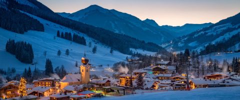 Saalbach village glowing at dusk, nestled between snow-covered alpine peaks