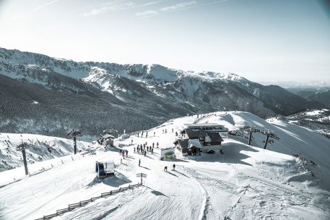 Snowy mountain ski resort with ski lifts and a scenic view of the forested valley below.