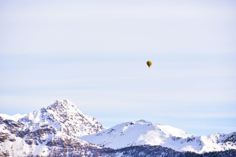Hot air balloon floating above snow-capped mountains
