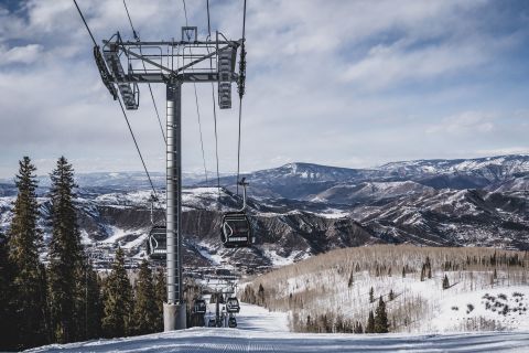 Ski lift leading up a mountain with a view of expansive snowy hills and valleys