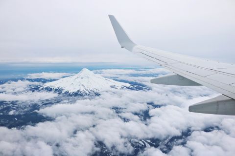 airplane flying over a snowy mountain peak 