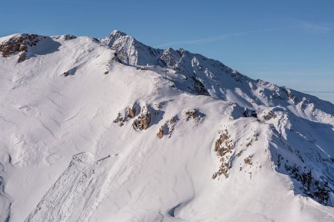 A small alpine village with snow-covered houses and a white church surrounded by mountains.