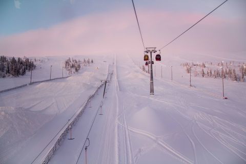 Ski lift ascending a snowy slope at Ylläs Ski Resort in Finland during a pink-hued winter sunrise