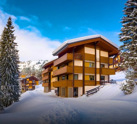 Snow-covered apartment buildings in a ski resort with a clear blue sky