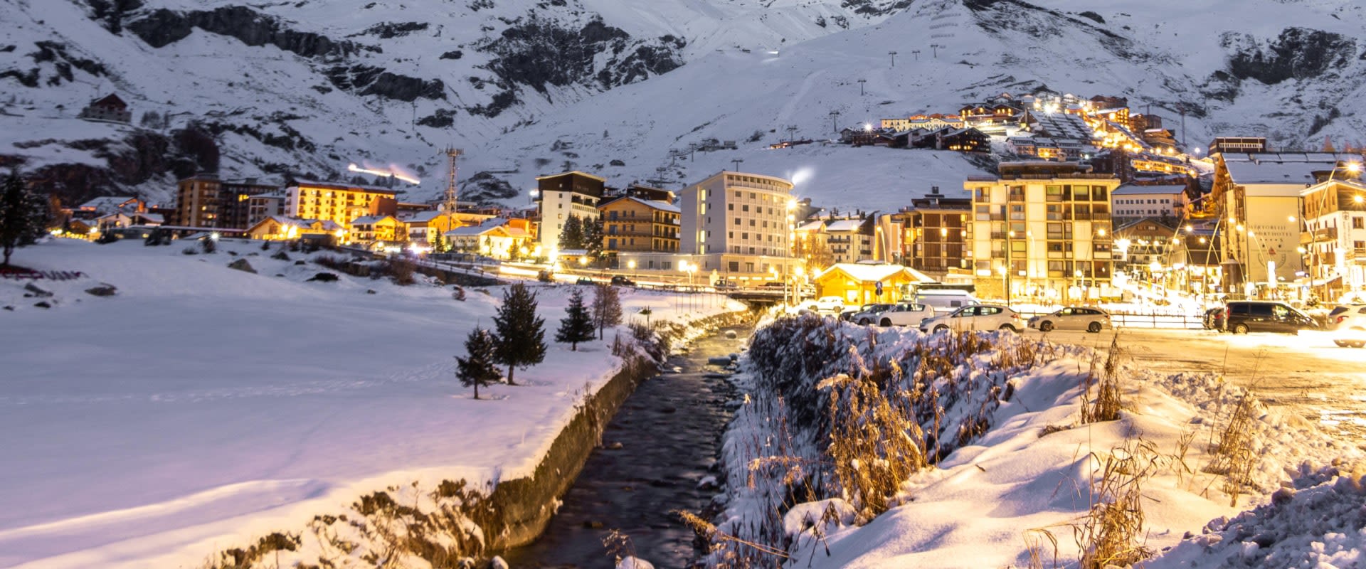 Night view of a snowy Cervinia with illuminated buildings and mountains in the background