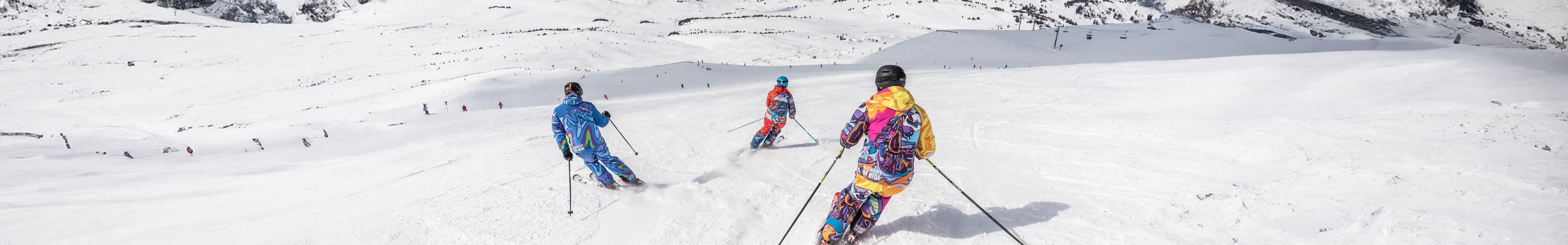 Trois skieurs dévalant une piste enneigée pendant les vacances de Pâques 2027.