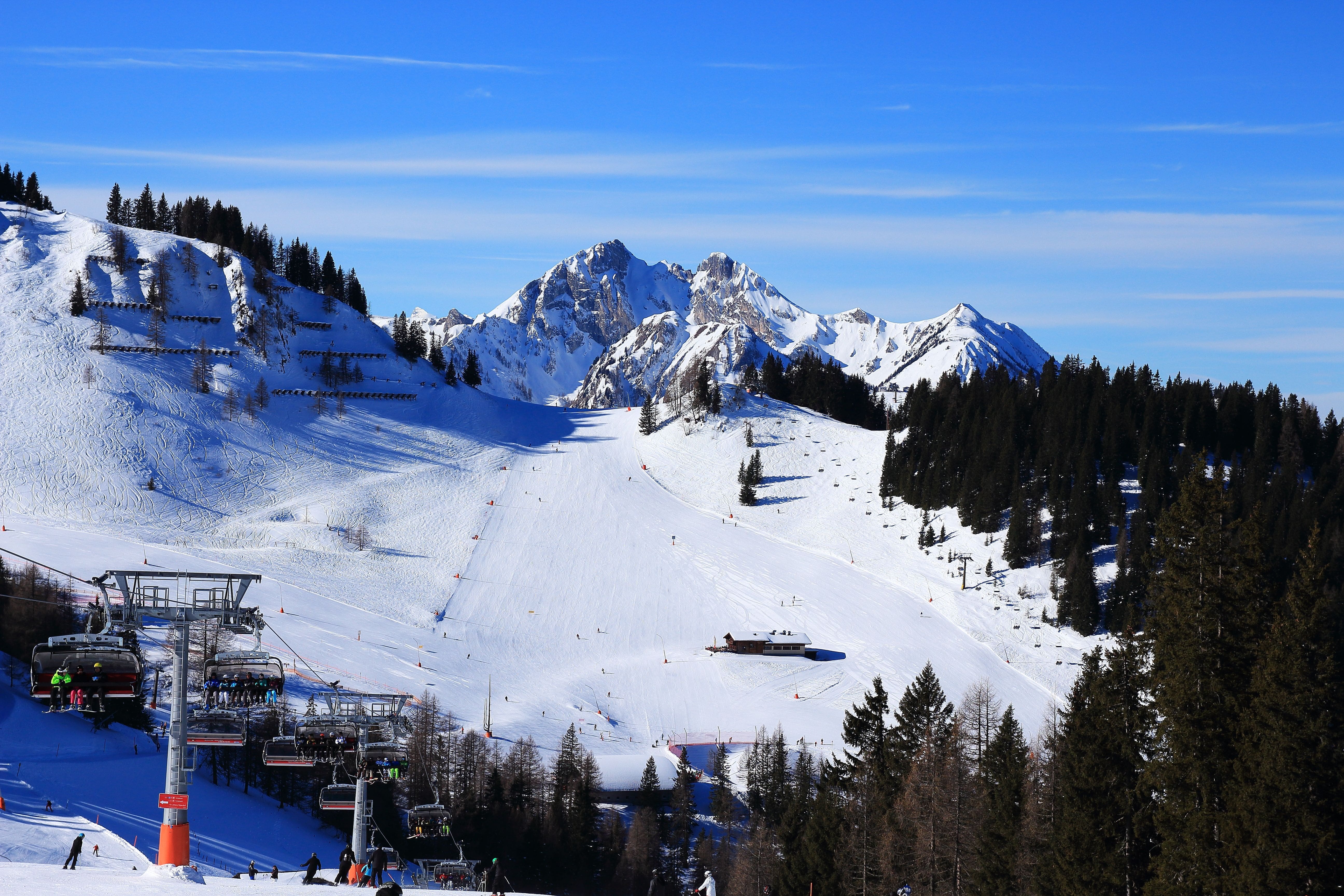 Ski slopes with chair lifts in the foreground and a mountain range in the distance on a sunny day.