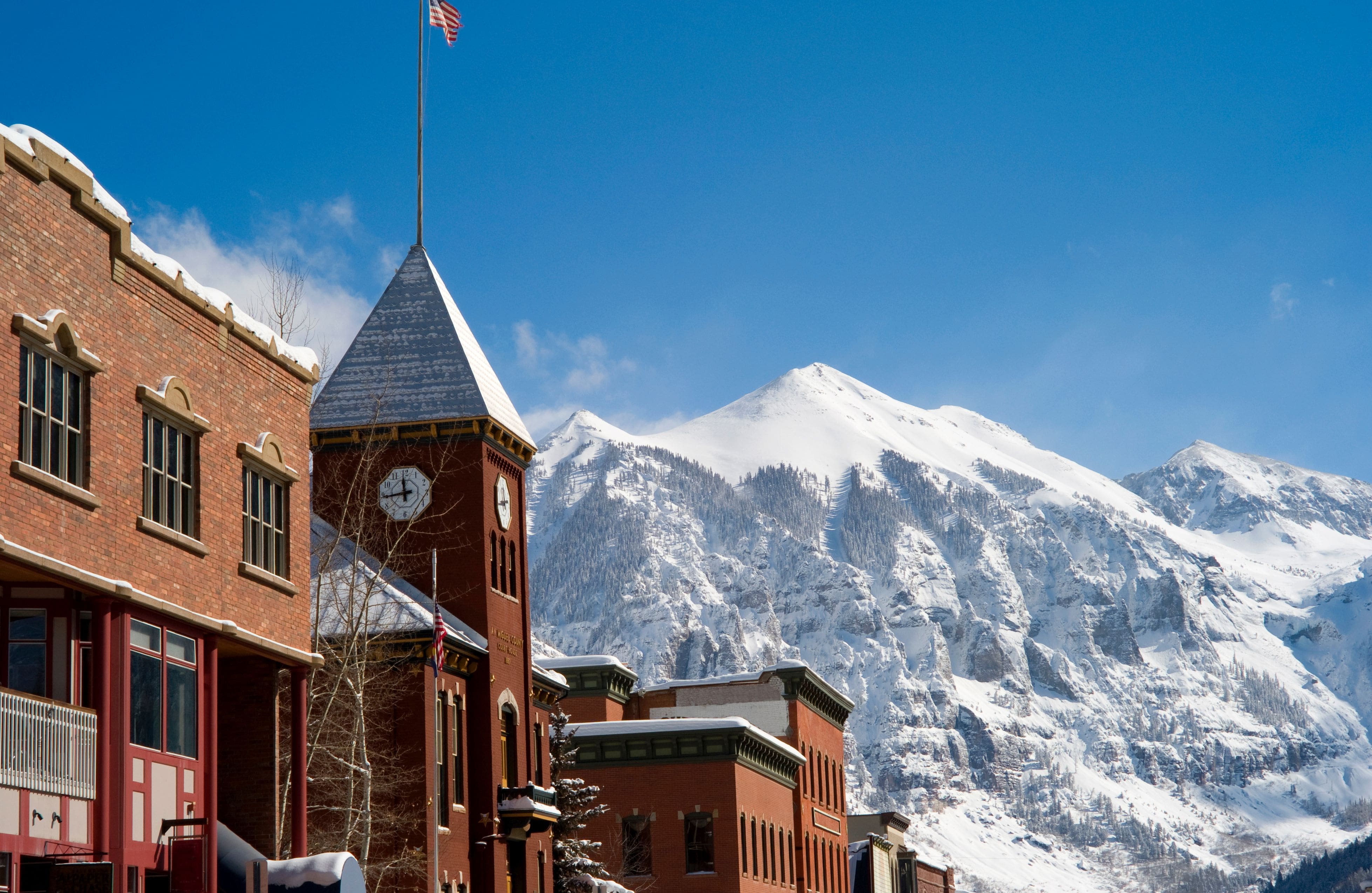 A snowy town in Telluride, Colorado, with a clocktower in the foreground and mountains in the background