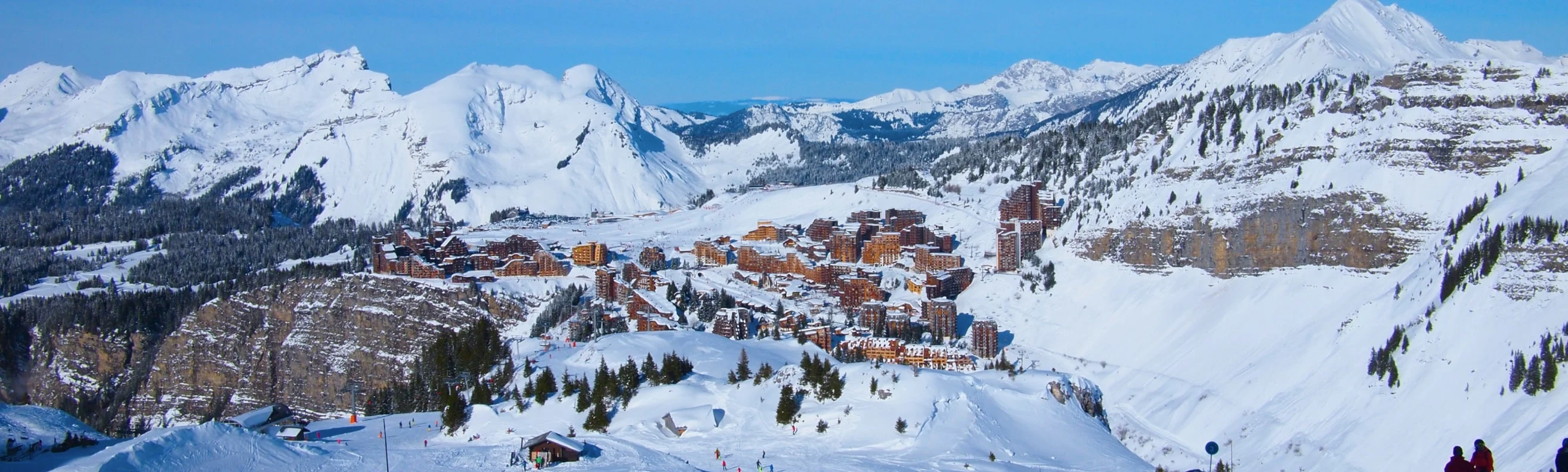 Aerial view of the unique cliff-top village of Avoriaz, surrounded by snowy peaks, with ski runs and mountain lodges in sight
