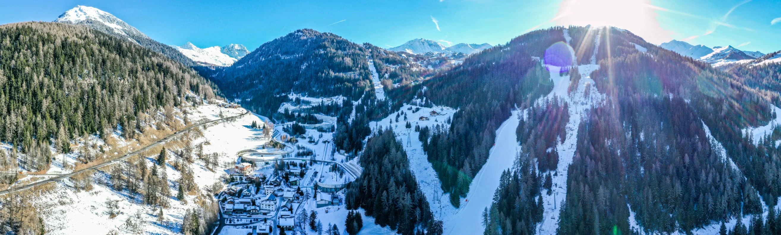 Aerial view of La Plagne village nestled among forested slopes and snowy mountains on a bright winter day