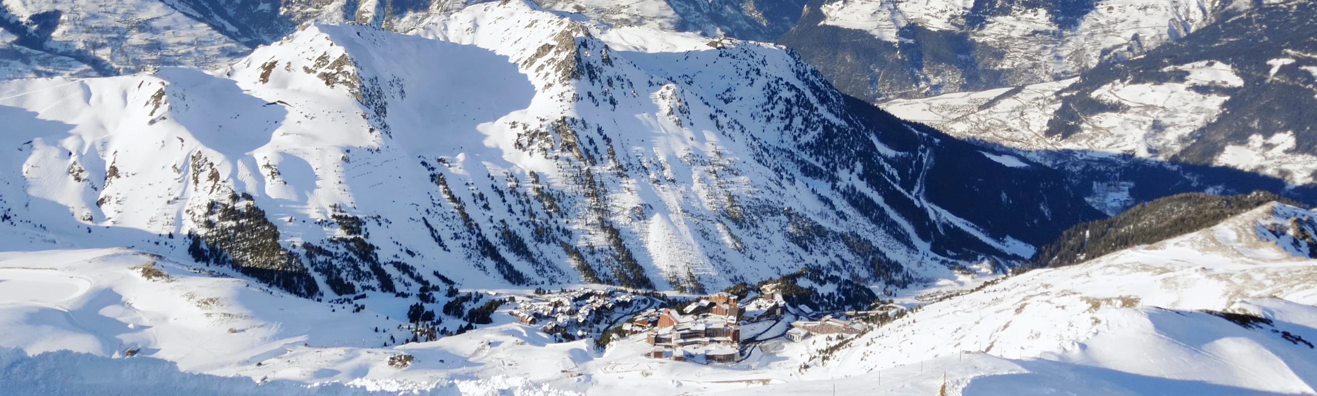 Les Arcs ski resort with modern and wooden buildings nestled in a snowy valley, surrounded by mountains