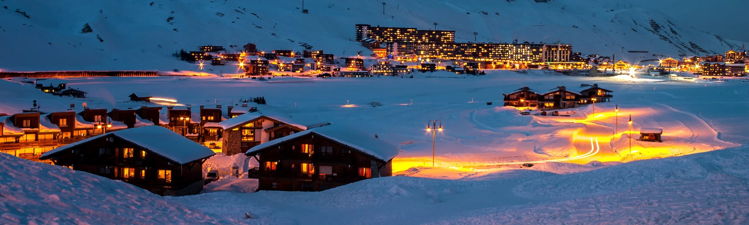 Night view of Tignes with its warm lights glowing across snow-covered chalets and modern ski resort buildings
