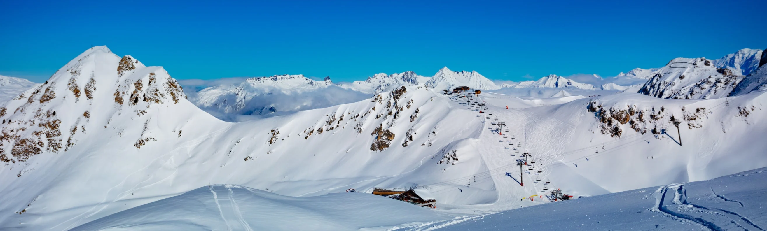 View of the vast Les Arcs ski area with chairlifts traversing the snowy slopes, surrounded by dramatic mountain peaks
