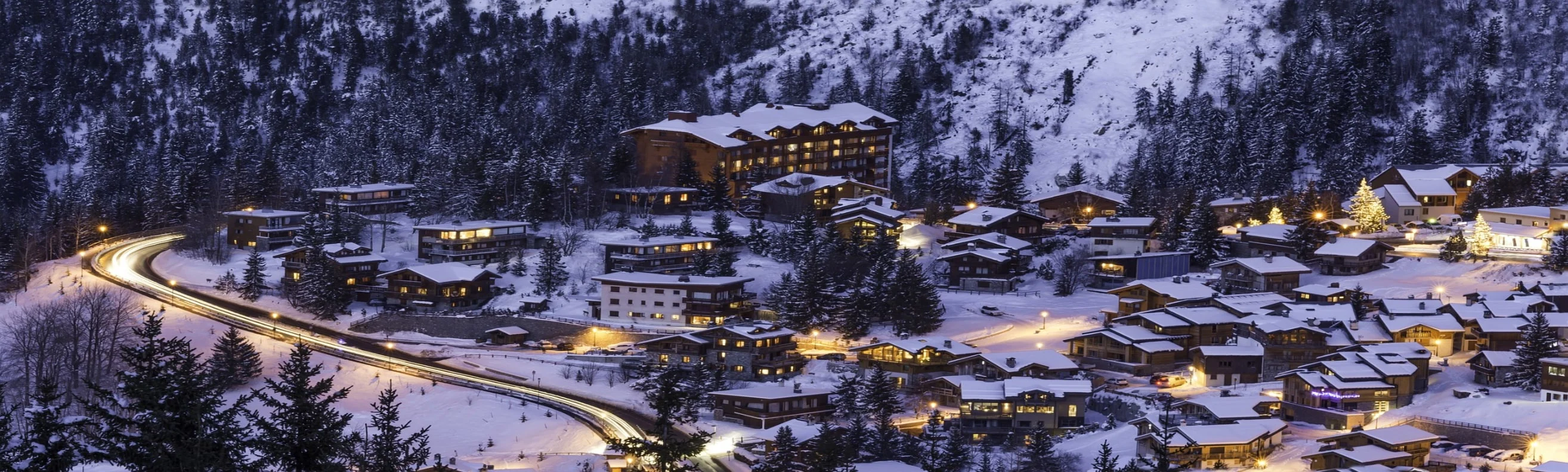Nighttime view of illuminated chalets and buildings in Courchevel