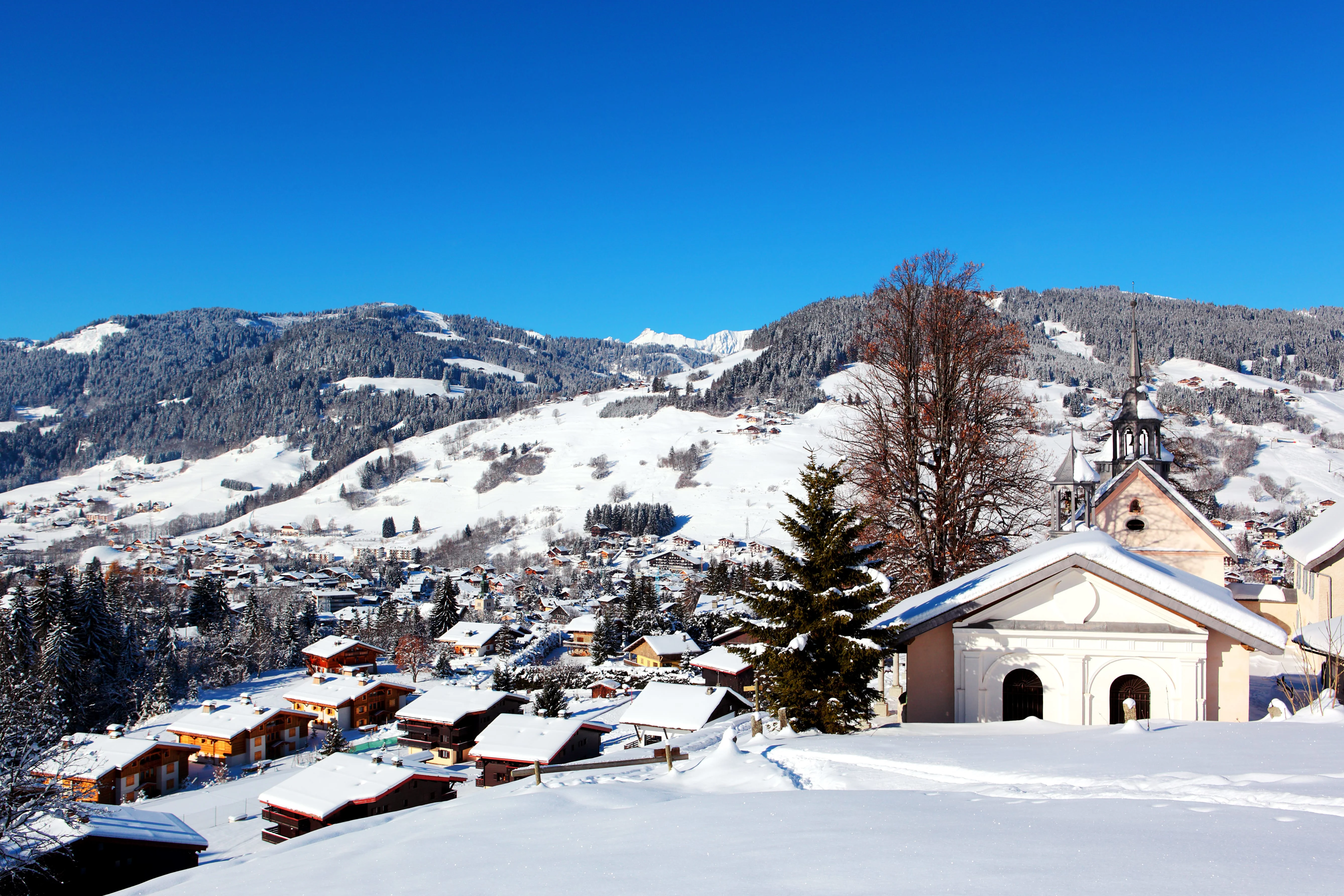 View of Megeve from a high vantage point, with a church and snow-covered rooftops