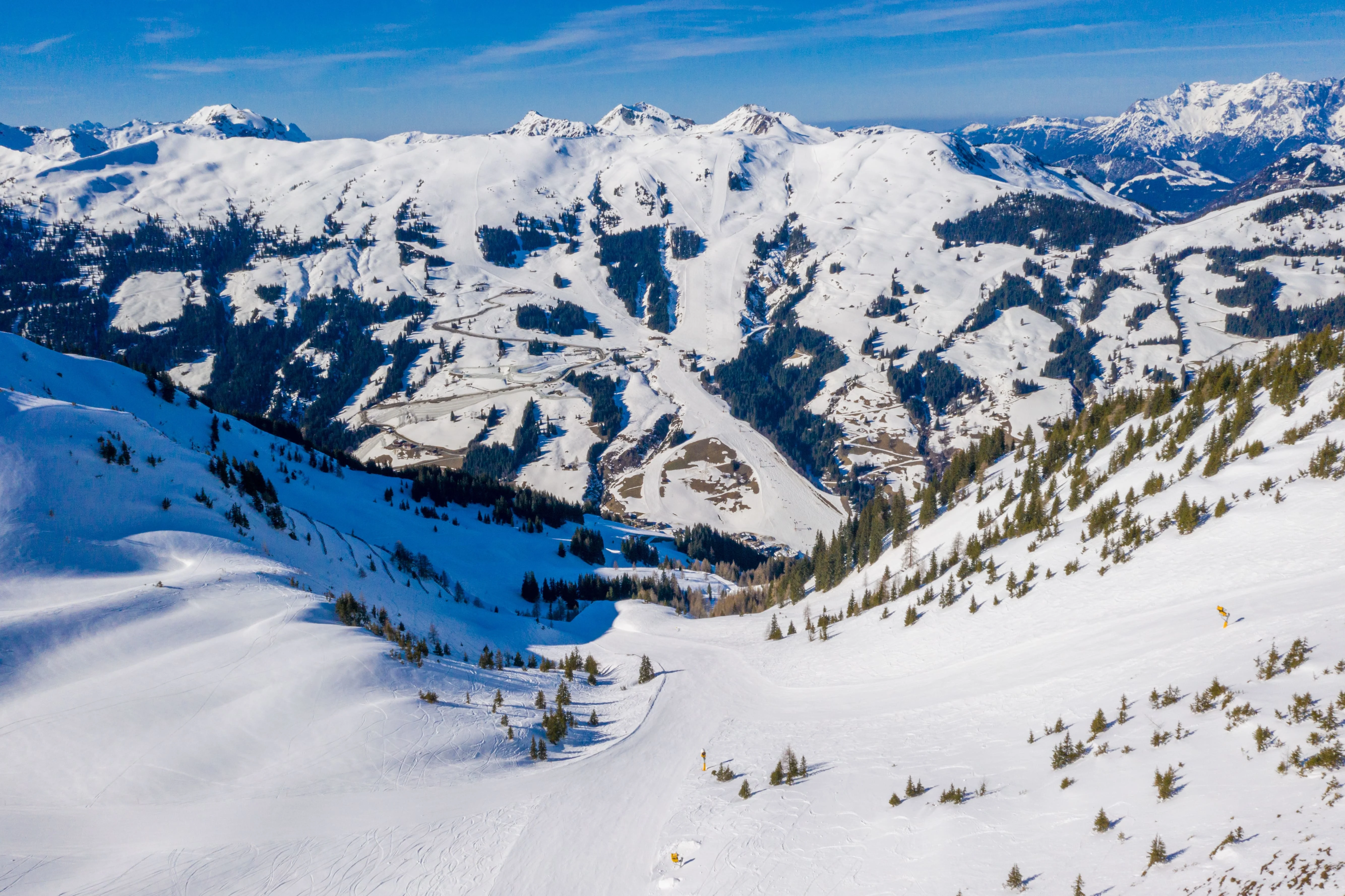 Wide panoramic view of snow-covered mountain peaks under a blue sky