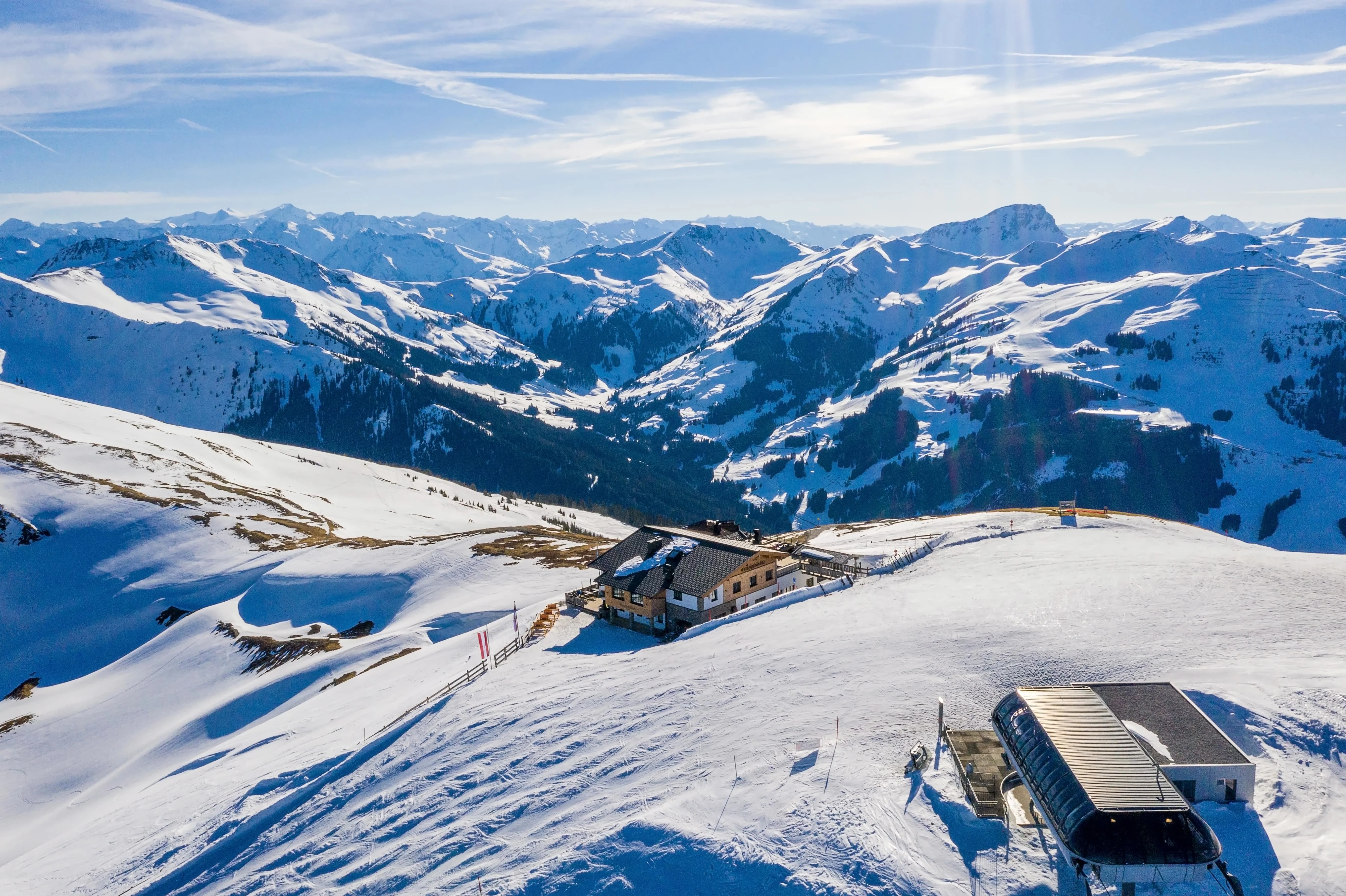 Ski lift and mountain hut on a snowy slope with expansive views of snow-covered peaks