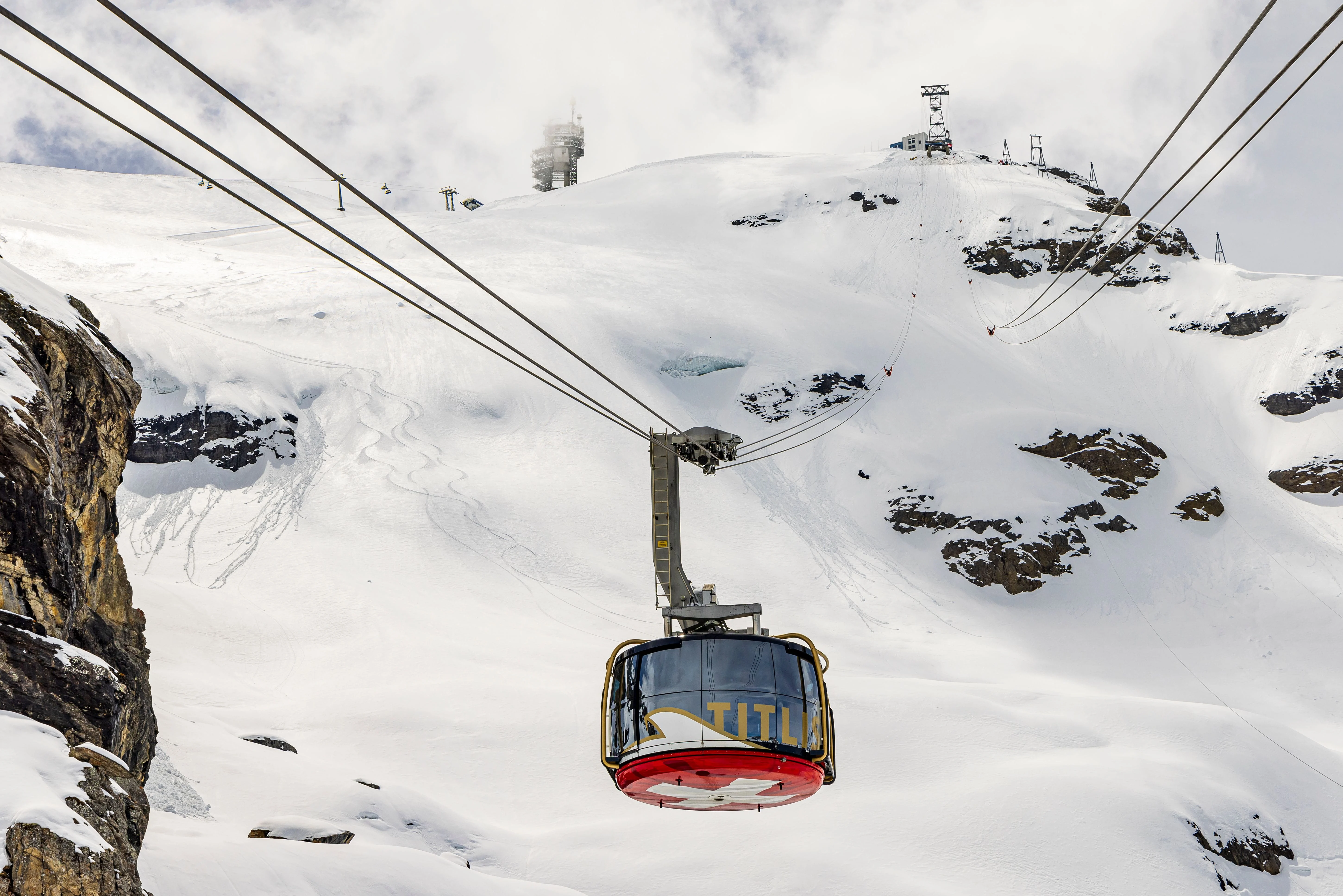 Cable car ascending snowy slopes with Mount Titlis summit in the background