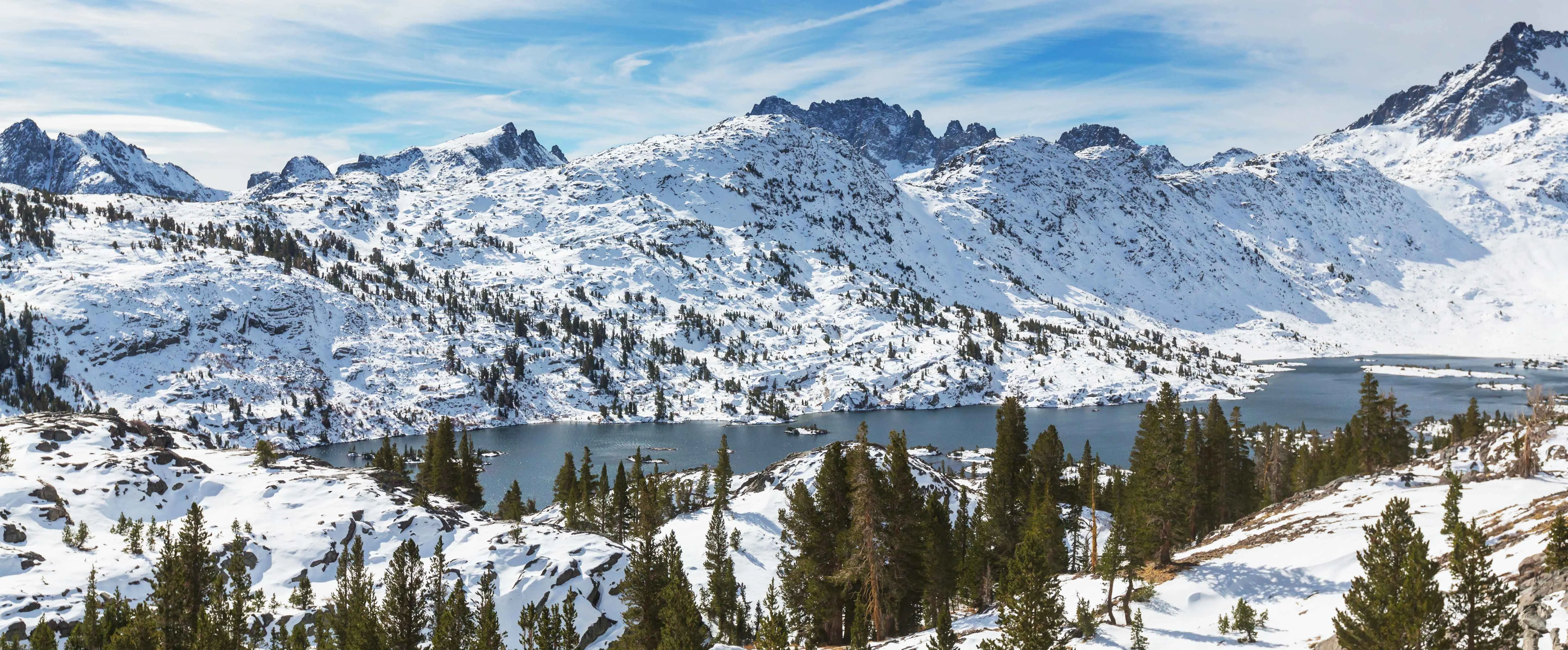 Sierra Nevada winter landscape with a lake and snowy mountain peaks on the background