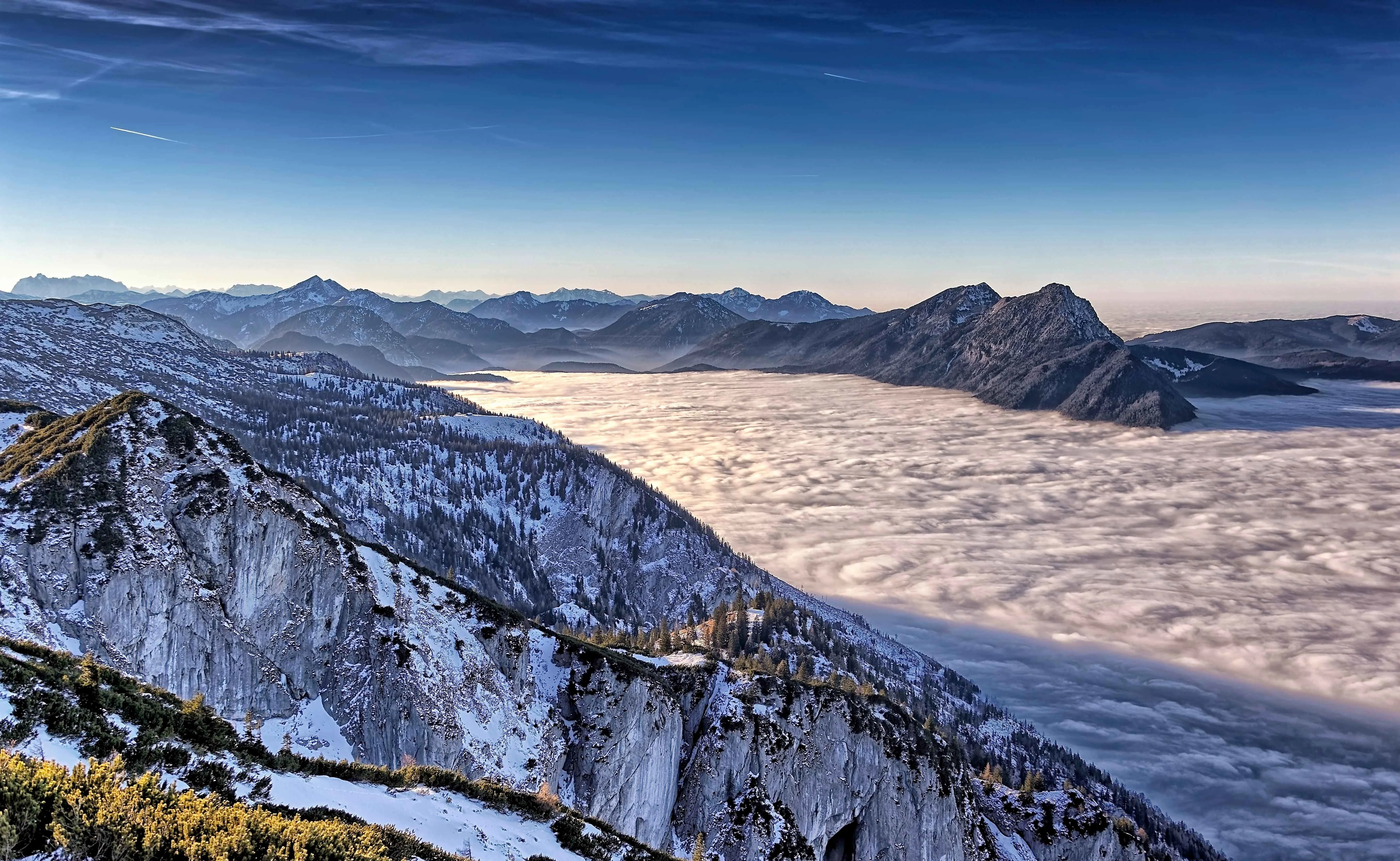 Snow-covered peaks of the Austrian Alps with a sea of clouds in the valley