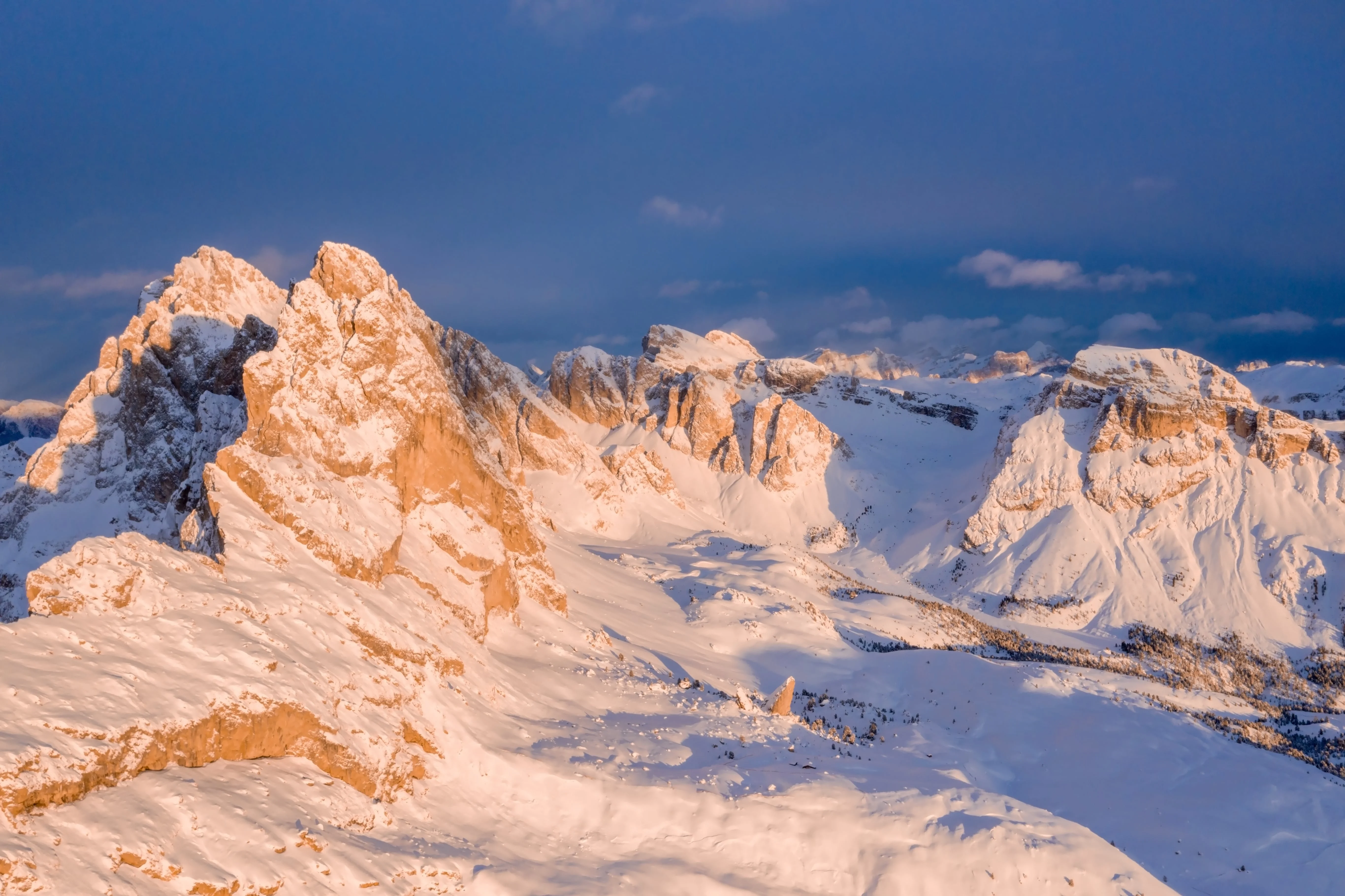  A glowing, orange-tinted sunset illuminates jagged snow-covered peaks