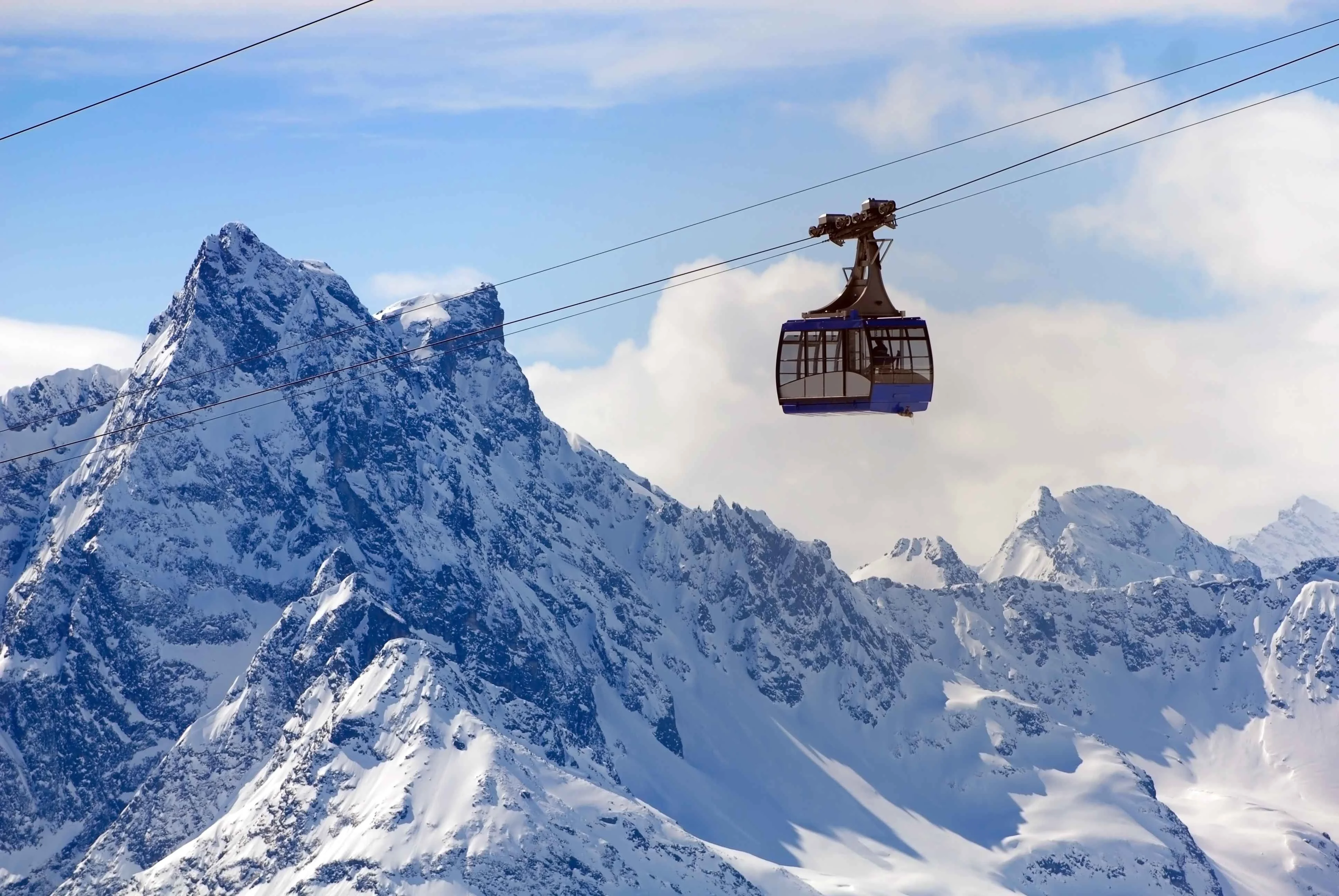 Blue gondola lift ascending snowy peaks in the Austrian Alps