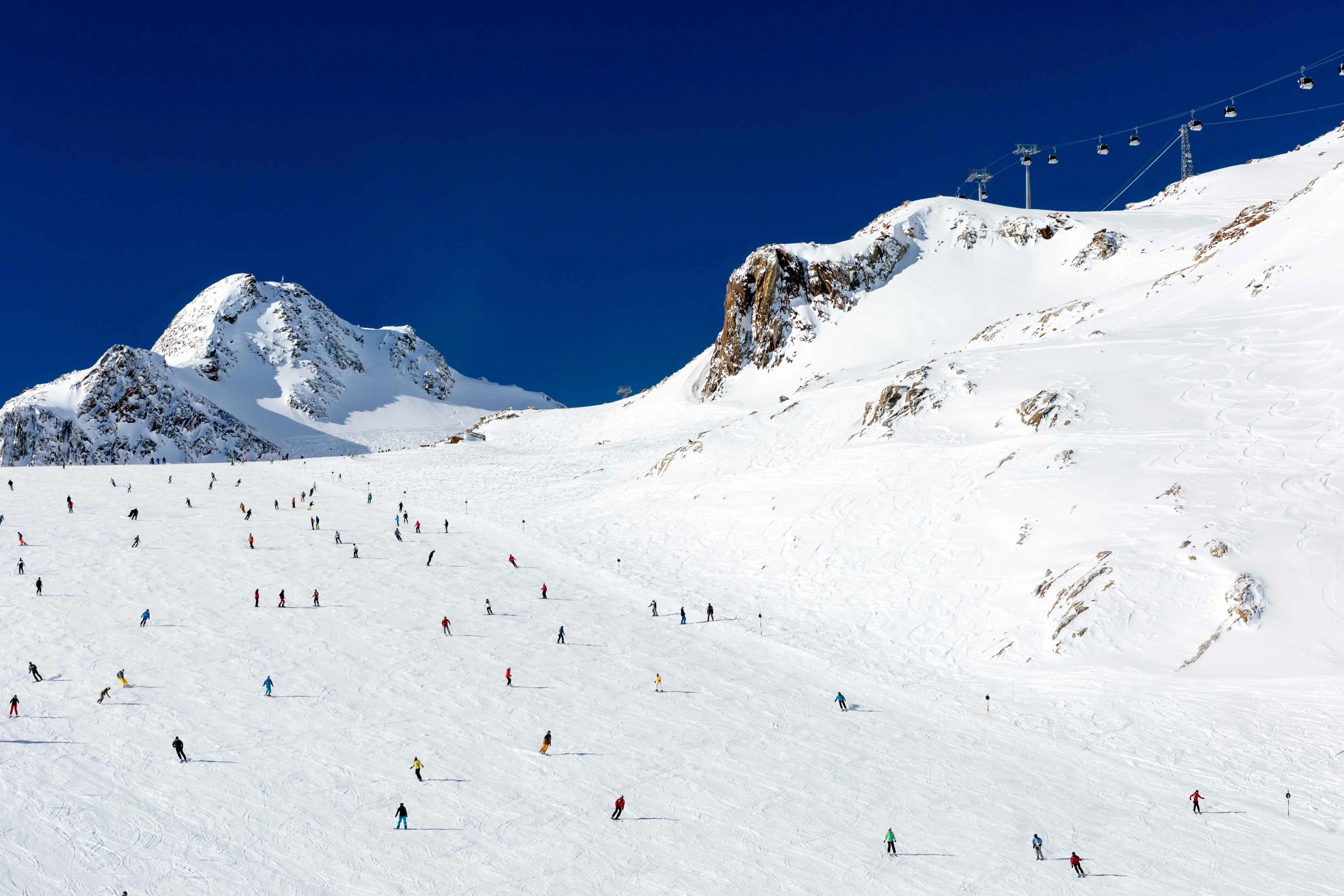 Ski piste with skiers under a blue sky