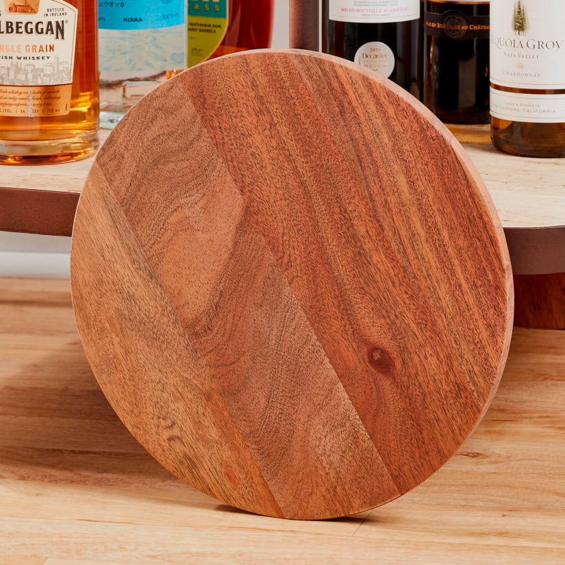 Round wooden tray resting against bottles on bar