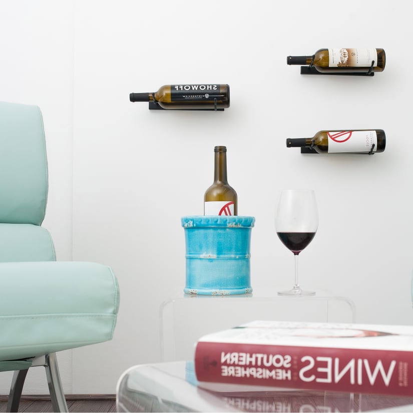 Multiple wall-mounted wine bottle racks with a glass of wine