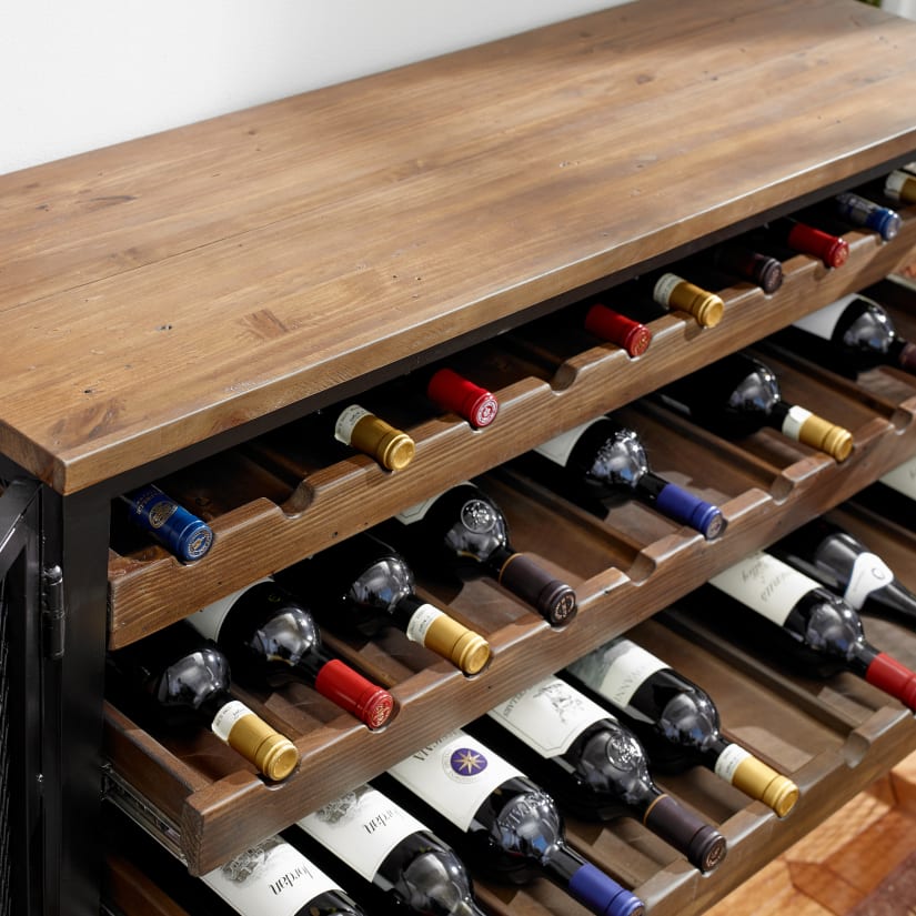 Close-up of the wine cabinet top and wine bottle necks resting in wooden slots on shelves.