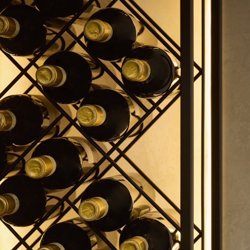 Close-up of wine bottles stored in a black iron rack with LED lighting.