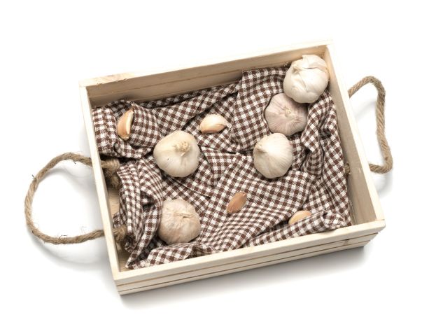 masanın üstünda bir ahşap kutu içerisinde sarımsaklar gözüküyor