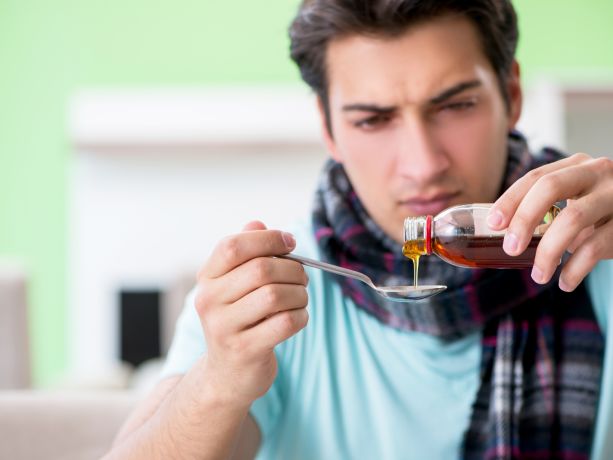 Yetişkin bir erkek kaşıkla şurup içiyor