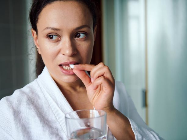 elinde bir bardak su ile iburamin cold yutan bir kadın