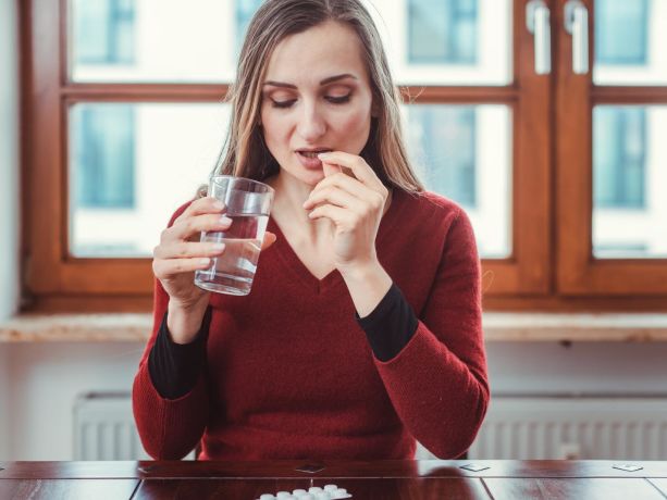 elinde bir su bardağı ile ilacın nasıl kullanıldığını gösteren yetişkin 