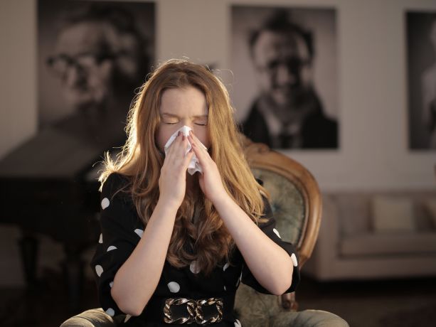 hapşurduğu için burnunu silen bir kadın