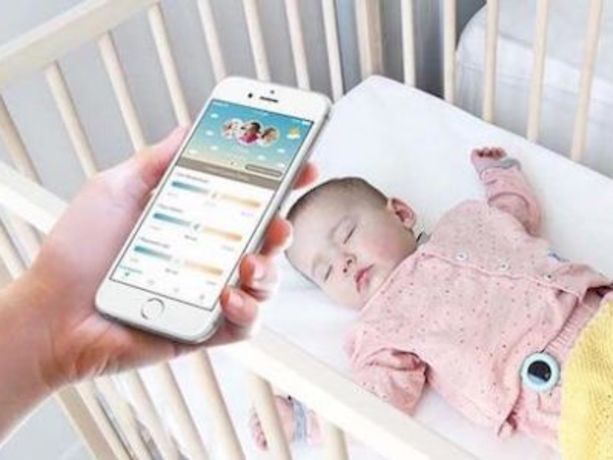 elinde bebek telsizi olan bir ebeveyn  bebeğin yanında duruyor