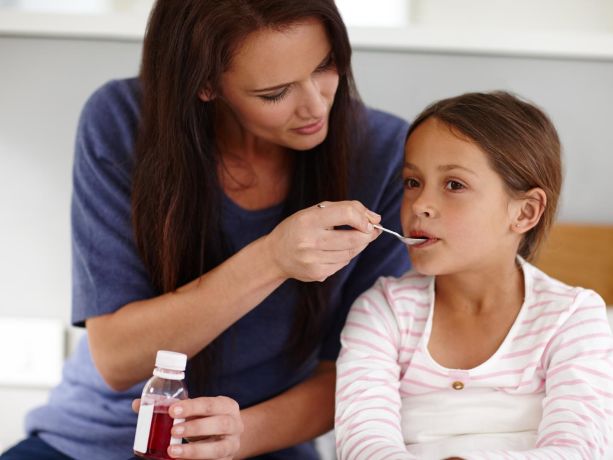 Bir anne çocuğuna kaşıkla şurup veriyor.