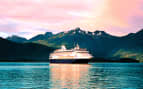 Holland America cruise ship cruises past mountains